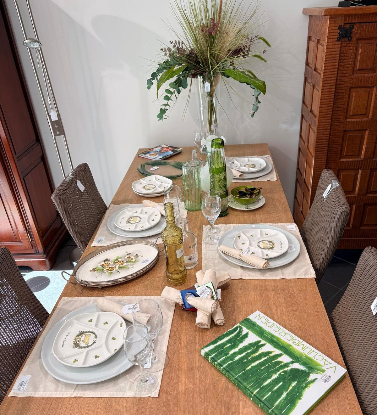 Houten eettafel gedekt met vintage servies, glaswerk en een droogboeket